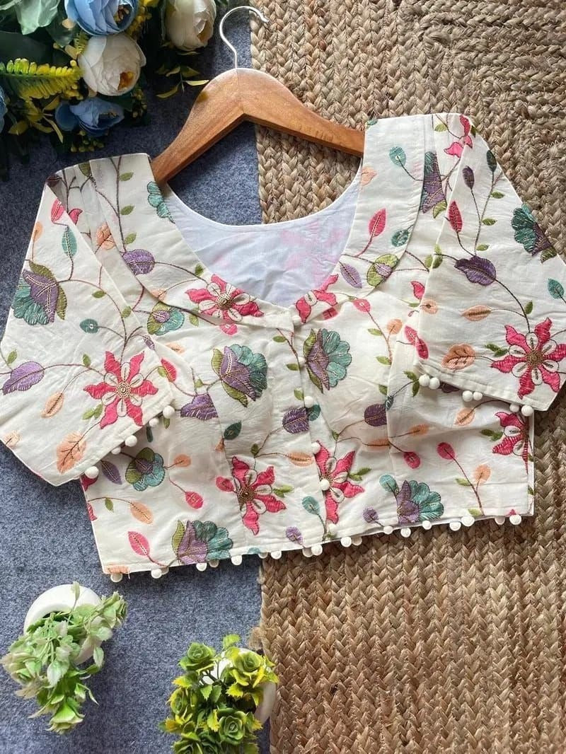 AMAB white Camric cotton blouse with floral embroidery, sequence work, and pom-pom trim. Padded and dyeable.