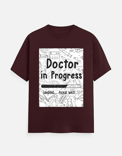 AMAB Doctor in Progress Loading Please Wait graphic t-shirt in maroon cotton with medical icons and loading bar design.